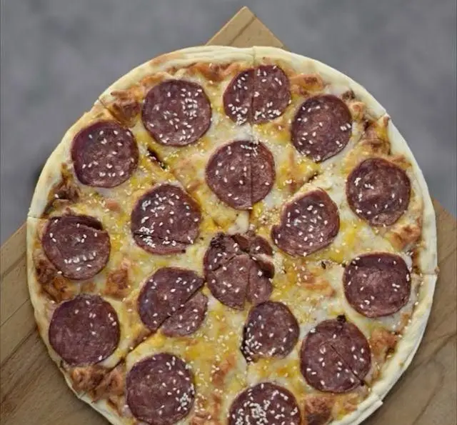 پیتزا پپرونی و پنیر فراوان با دانه های کنجد، ارائه شده در کافه رستوران پلاک ٥، یک غذای لذیذ و محبوب برای تمامی سلیقه‌ها.