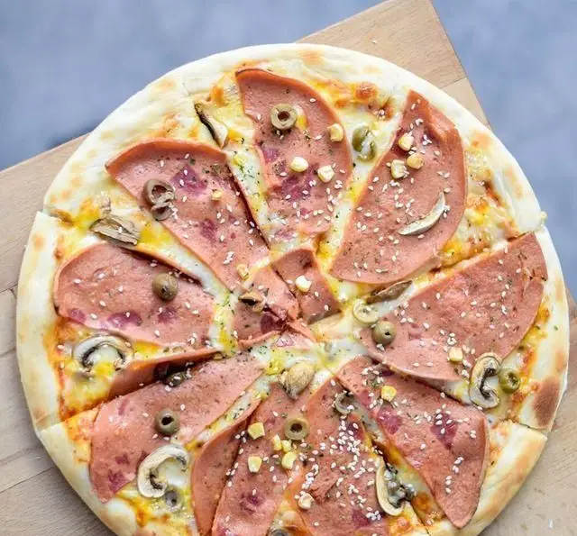 تصویر پیتزای كالباس و قارچ کافه رستوران پلاک ٥، با برش های منظم، تاپینگ های تازه شامل زیتون و کنجد، مناسب برای دوستداران غذای ایتالیایی.