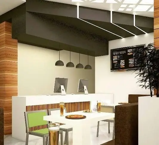 فضای داخلی مدرن فست فود دریم، شامل میز و صندلی‌های شیک، پیشخوان سفارش با دو مانیتور، منوی دیجیتال و دکوراسیون دلنشین و چوبی.