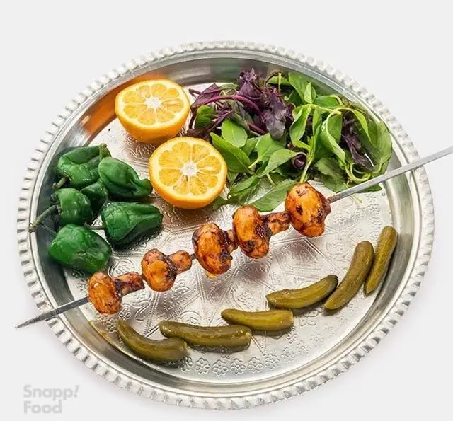 یک سیخ کباب قارچ خوشمزه و فلفل کبابی، همراه با لیمو ترش تازه، سبزیجات معطر و خیارشور، از منوی متنوع رستوران نارکباب.