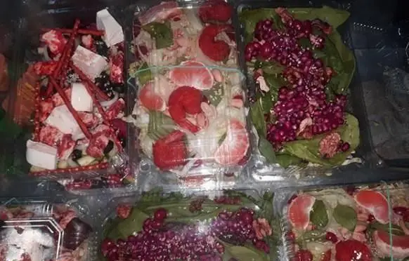 تصویری از انواع سالادهای تازه و رنگارنگ پیتزا تام، شامل سالاد انار با اسفناج، سالاد میگو با گریپ فروت و غذاهای آماده در ظروف یکبار مصرف