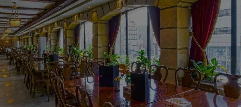 تصویری از سالن غذاخوری کافه رستوران ارکیده (شعبه آرژانتین)؛ فضایی مجلل با طاق‌های سنگی، میزهای چوبی و نمایی زیبا از شهر.