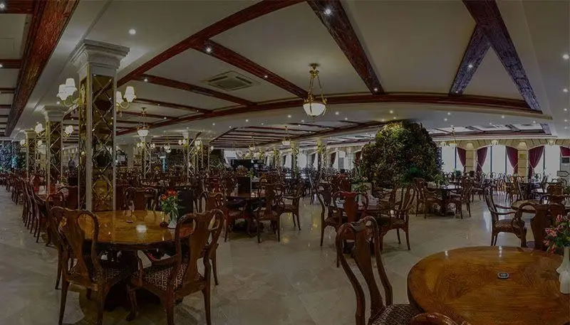 فضای داخلی وسیع و شیک کافه رستوران ارکیده شعبه آرژانتین با میز و صندلی‌های چوبی، دکوراسیون زیبا و محیطی دلنشین برای پذیرایی.