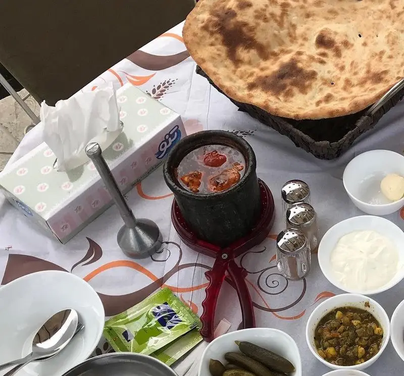 سفره‌ای دلنشین از دیزی آبگوشت سنتی لذیذ در رستوران ماه و مهر، با نان تازه تنوری، ماست، ترشی و مخلفات کامل ایرانی.