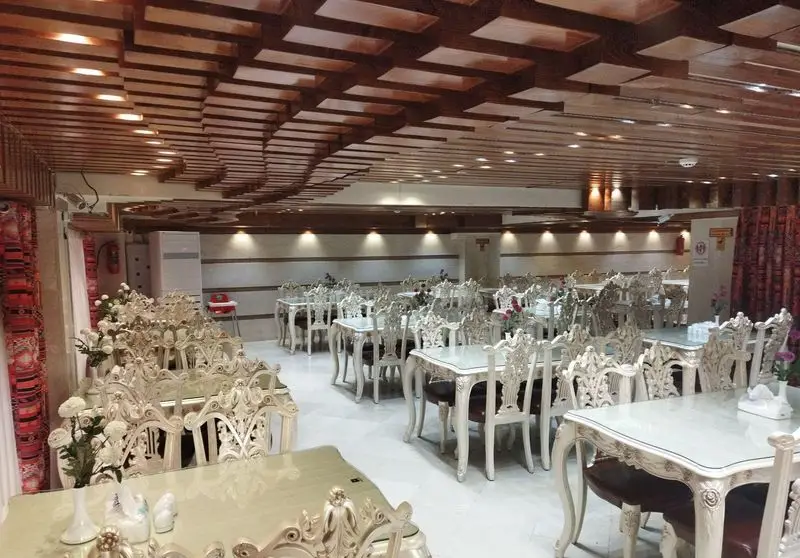 فضای داخلی رستوران ماه و مهر با دکوراسیون مجلل، شامل میز و صندلی‌های شیک و کلاسیک، سقف چوبی زیبا و نورپردازی گرم برای تجربه‌ای دلنشین.