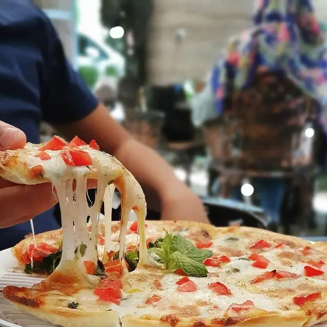 پیتزای خوشمزه و تازه کافه رستوران گیاهی مادو با پنیر کش‌دار و گوجه فرنگی، تجربه‌ای دلپذیر از غذای گیاهی