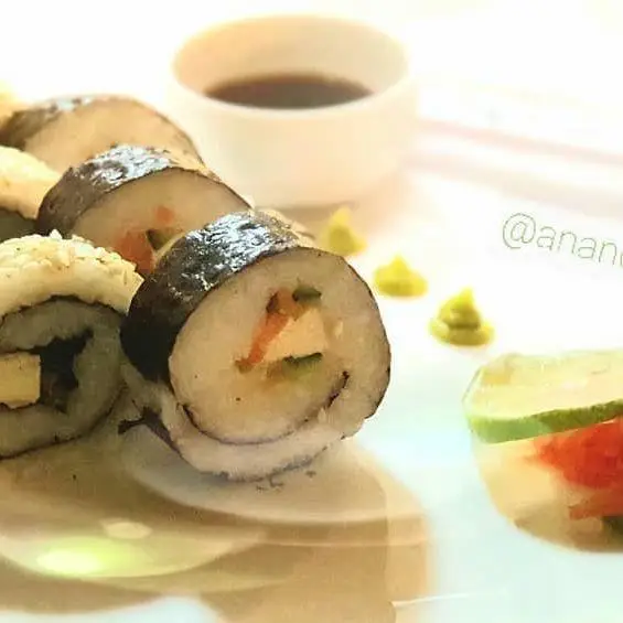 رول‌های سوشی گیاهی متنوع کافه رستوران گیاهی مادو، با واسابی، سس سویا و برش لیمو. انتخابی سالم و لذیذ.