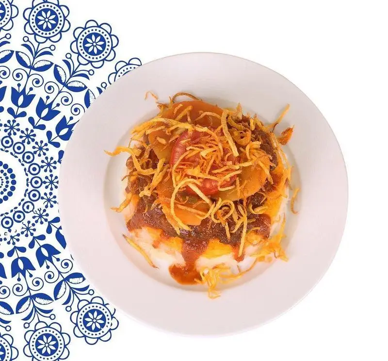 تصویری جذاب از یک بشقاب غذای سنتی خاص و خوش‌عطر رستوران سنتی خوان کرم، با تزئینات طلایی و بافت‌های متنوع.