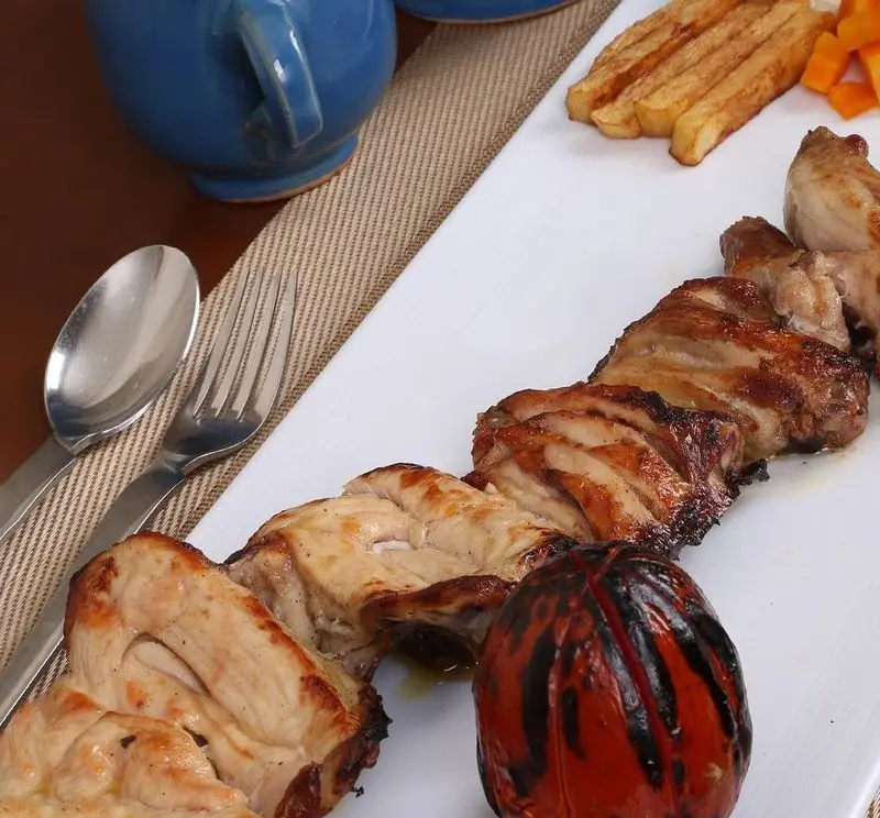 کباب مرغ و گوجه کبابی در رستوران سنتی خوان کرم، با سیب زمینی سرخ کرده و ظرف آبی. غذای اصیل و خوشمزه ایرانی.