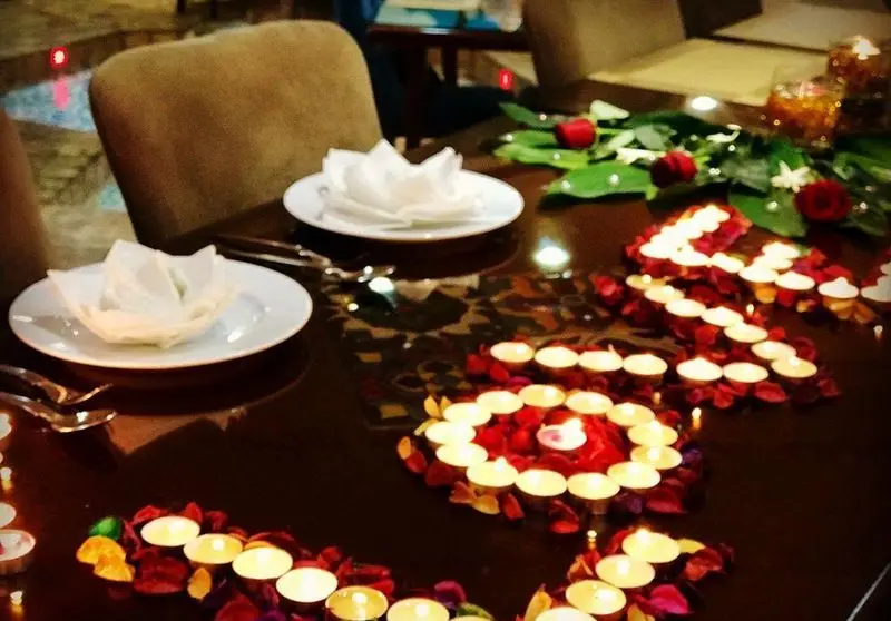 دکوراسیون رمانتیک میز شام در رستوران سنتی خوان کرم با شمع‌آرایی زیبا و گلبرگ‌های رز، فضایی دلنشین برای مناسبت‌های خاص.