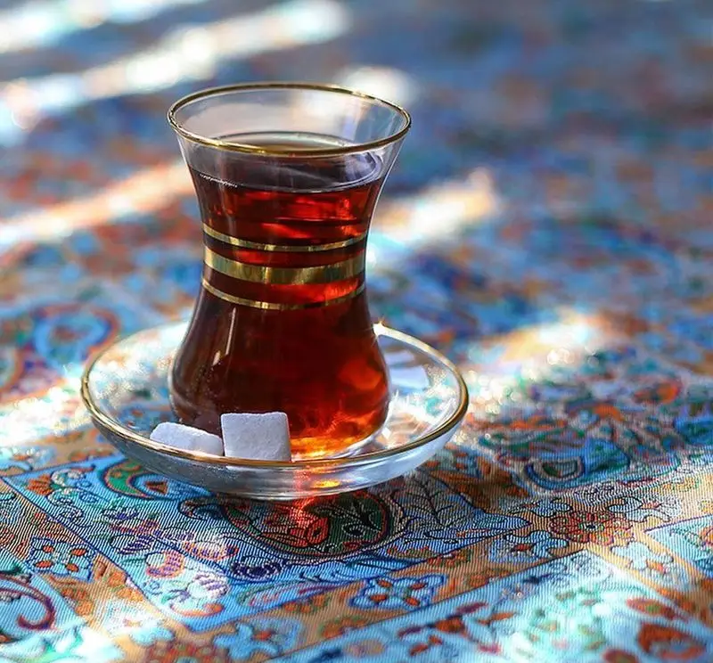 استکان چای داغ و سنتی روی رومیزی ترمه در رستوران سنتی خوان کرم. لذت نوشیدنی اصیل ایرانی در محیطی دلنشین و آرامش‌بخش.