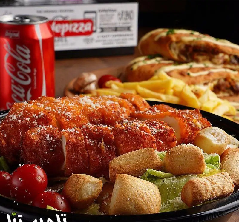 مرغ سوخاری و کریسپی تله پیتزا با چاشنی پنیر پارمزان، همراه سالاد سزار، سیب زمینی سرخ کرده و نان سیر. غذایی لذیذ از منوی فست فود تله پیتزا.