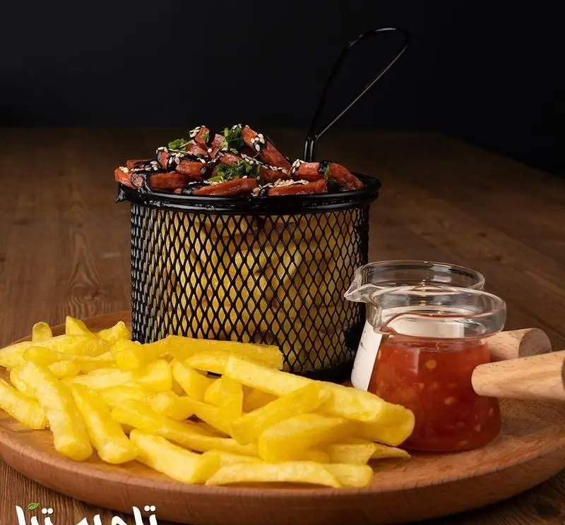 سیب زمینی سرخ کرده پر و پیمان به همراه سوسیس، سبزیجات و سس‌های متنوع فست فود تله پیتزا، تجربه‌ای خوشمزه از یک غذای آماده.