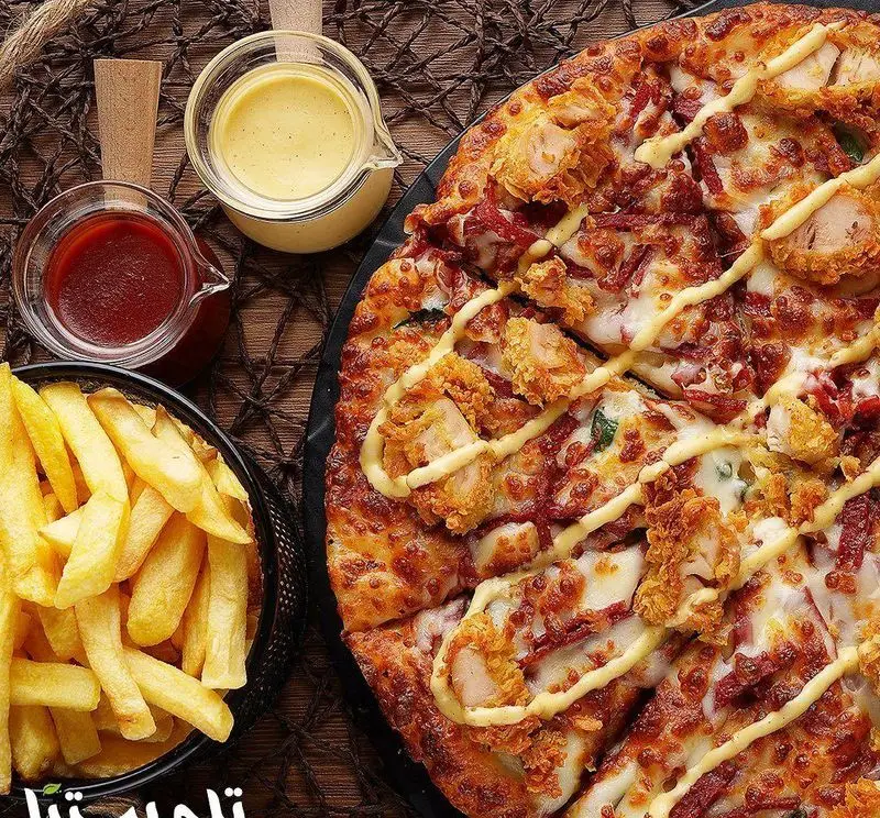 پیتزا لذیذ تله پیتزا با مرغ سوخاری و سس مخصوص، در کنار سیب زمینی سرخ کرده طلایی و سس های کچاپ و پنیر. فست فود تله پیتزا.