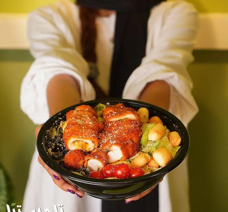 سرو غذای خوشمزه فست فود تله پیتزا شامل سینه مرغ سوخاری پر شده، سالاد سبز، گوجه و زیتون در کاسه