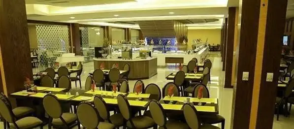 فضای داخلی بزرگ و نورانی رستوران شاین با میزهای چیدمان شده آماده پذیرایی و بوفه متنوع غذا، دکوراسیون مدرن و شیک.