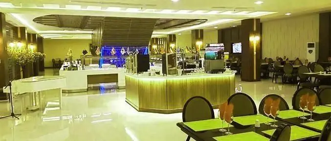 نمایی گسترده از فضای داخلی مدرن و شیک رستوران شاین با بوفه مرکزی بزرگ، میزهای غذاخوری چیده شده و پیانوی سفید.