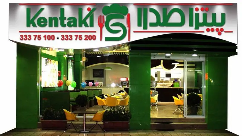 نمای بیرونی جذاب فست فود و پیتزا صدرا در شب، با تابلوی روشن Kentaki و اطلاعات تماس 33375100 و 33375200، آماده پذیرایی از مشتریان.