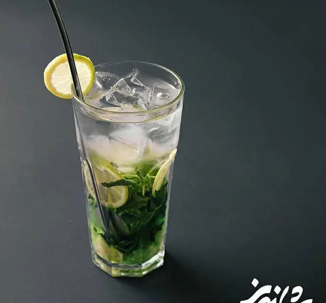 تصویری از یک موهیتو لیمو و نعنای خنک در لیوان بلند با تکه های یخ و برش های لیمو، نوشیدنی عالی و تازه برای لذت بردن در رستوران شاندیز.