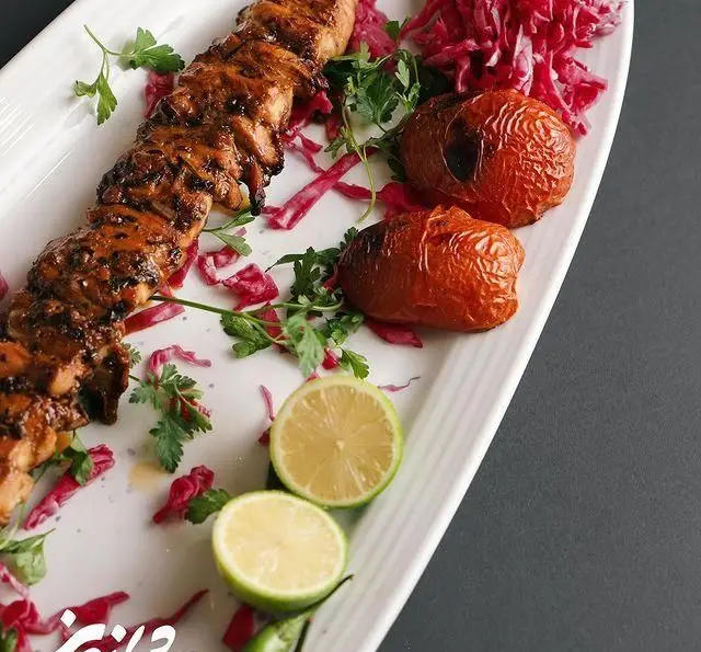 جوجه کباب لذیذ و خوش طعم رستوران شاندیز، غذای اصیل و باکیفیت ایرانی، همراه گوجه کبابی، لیمو و سبزیجات تازه، مناسب برای ناهار و شام.