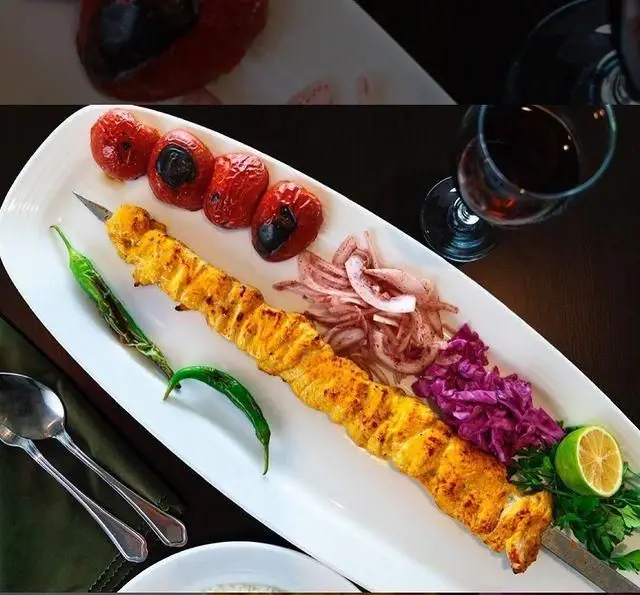 یک سیخ جوجه کباب زعفرانی و لذیذ در رستوران شاندیز، با گوجه کبابی، پیاز، کلم بنفش، فلفل و نوشیدنی. لذت طعم اصیل ایرانی.