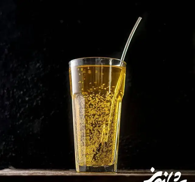 یک لیوان نوشیدنی گازدار طلایی و گوارا در رستوران شاندیز، آماده سرو برای مشتریان در محیطی دلنشین و آرام.