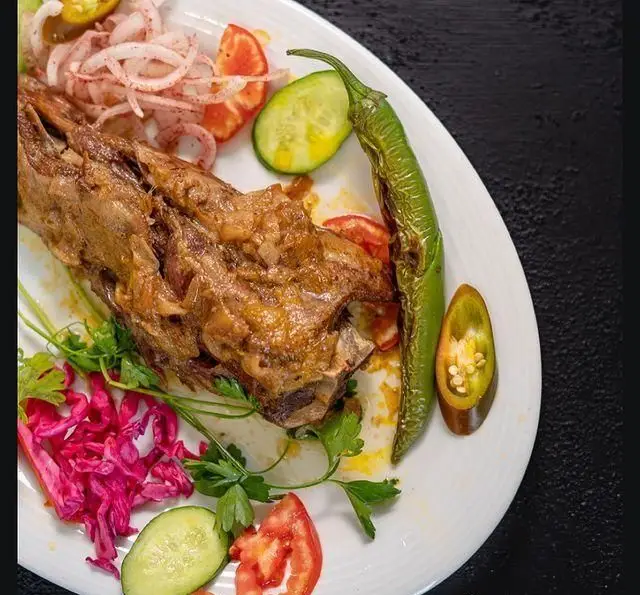 بشقاب اصلی رستوران شاندیز با گوشت بره پخته، تزئین شده با پیاز، خیار، گوجه فرنگی تازه، سبزی و فلفل سبز تند و اشتها آور.