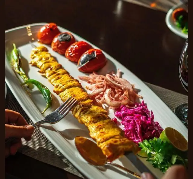 بشقاب لذیذ جوجه کباب زعفرانی رستوران شاندیز همراه با گوجه کبابی، پیاز، سبزیجات تازه و دورچین متنوع. تجربه طعم اصیل ایرانی.