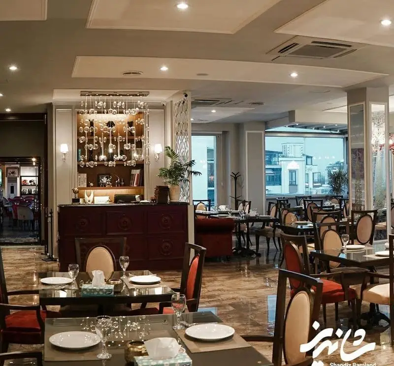 فضای داخلی لوکس و دلباز رستوران شاندیز باملند با میز و صندلی‌های شیک چیده شده و دکوراسیون چشم‌نواز، مناسب برای ناهار و شام.