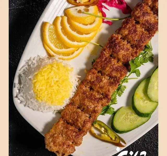 کباب کوبیده لذیذ رستوران شاندیز با برنج زعفرانی و سفید، ترشی، سبزیجات تازه و لیمو. غذای سنتی ایرانی خوشمزه.