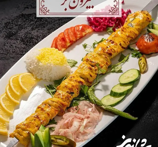 جوجه کباب لذیذ رستوران شاندیز همراه با برنج زعفرانی، گوجه کبابی، پیاز، خیار، لیمو و مخلفات سنتی ایرانی. بهترین غذای ایرانی.