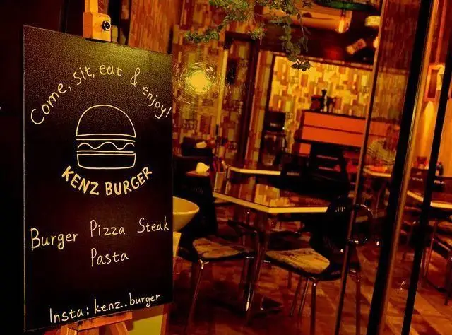 نمایی از تابلوی گچی فست فود کنز برگر حاوی منوی کامل شامل برگر، پیتزا، استیک و پاستا به همراه فضای داخلی گرم و دلنشین.