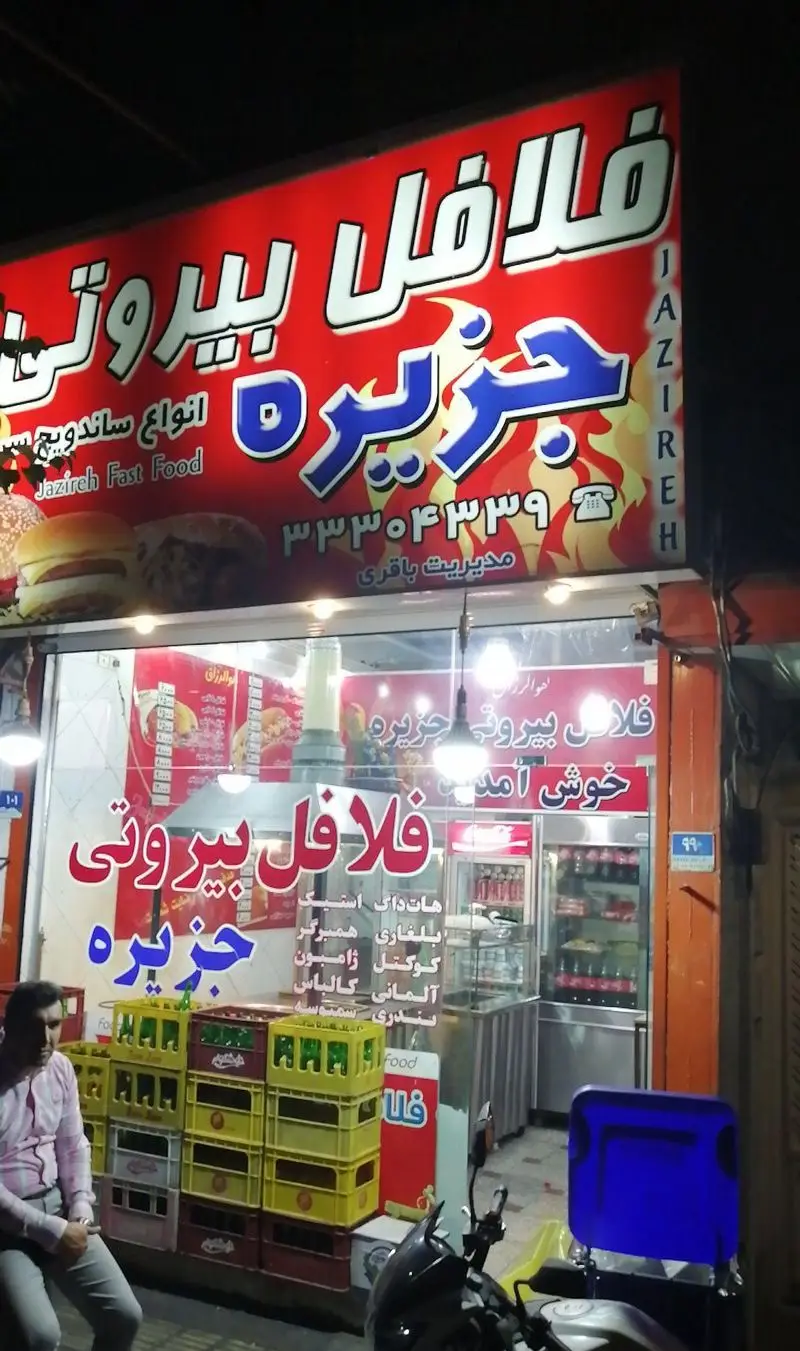 فست فود فلافل بیروتی جزیره: نمای بیرونی مغازه در شب، ارائه دهنده انواع ساندویچ، هات داک، همبرگر و غذاهای خوشمزه.