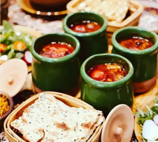 دیزی سنتی رستوران دیزی بار مزه بازار: چهار ظرف دیزی سبز با خورش، نان سنگک کنجدی و سبزیجات تازه. تجربه‌ای اصیل از غذای ایرانی.