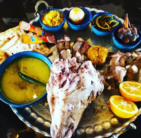 عکس سینی کامل کله پاچه سنتی و لذیذ در رستوران دیزی بار مزه بازار، شامل مغز، زبان، پاچه، آبگوشت و نان داغ ایرانی برای صبحانه.