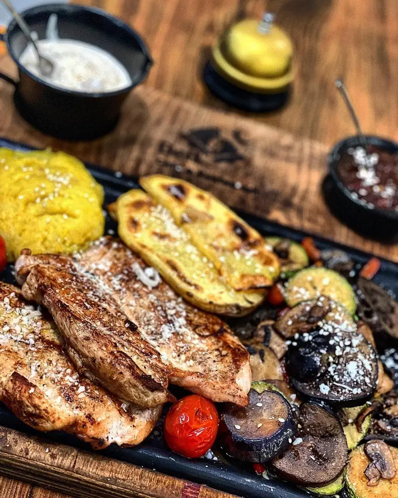 غذای اصلی بل کافه: بشقاب مرغ گریل با سبزیجات تازه، سیب زمینی و دورچین‌های متنوع و اشتهاآور.