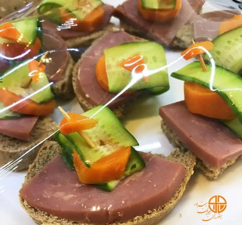 فینگرفودهای خوشمزه و زیبای ژامبون و خیار و هویج رستوران جوان هنرور ۲، مناسب پذیرایی و مجالس، با نان تازه و تزئینات شیک.