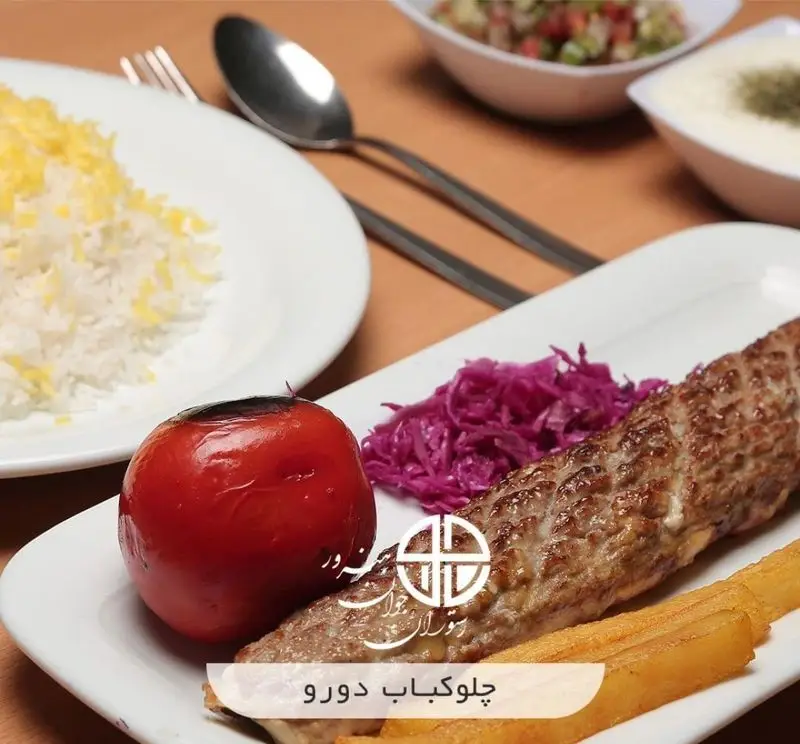 چلوکباب دورو لذیذ رستوران جوان هنرور ۲ با برنج زعفرانی، گوجه کبابی، سالاد کلم و سیب زمینی؛ غذای ایرانی با کیفیت.
