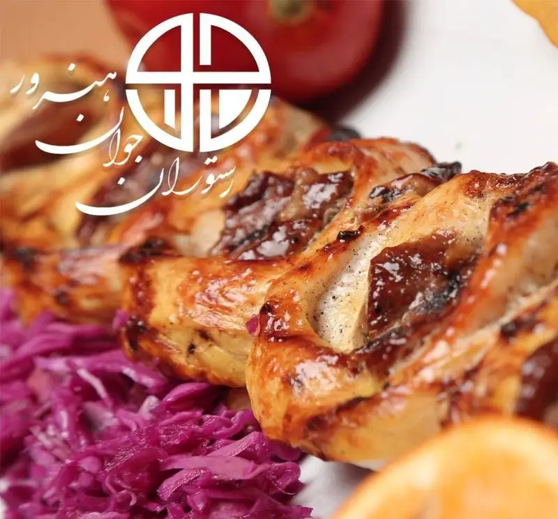 جوجه کباب طلایی و خوشمزه رستوران جوان هنرور ۲، غذای اصیل ایرانی با کلم بنفش و گوجه. لوگوی رستوران نیز مشخص است.