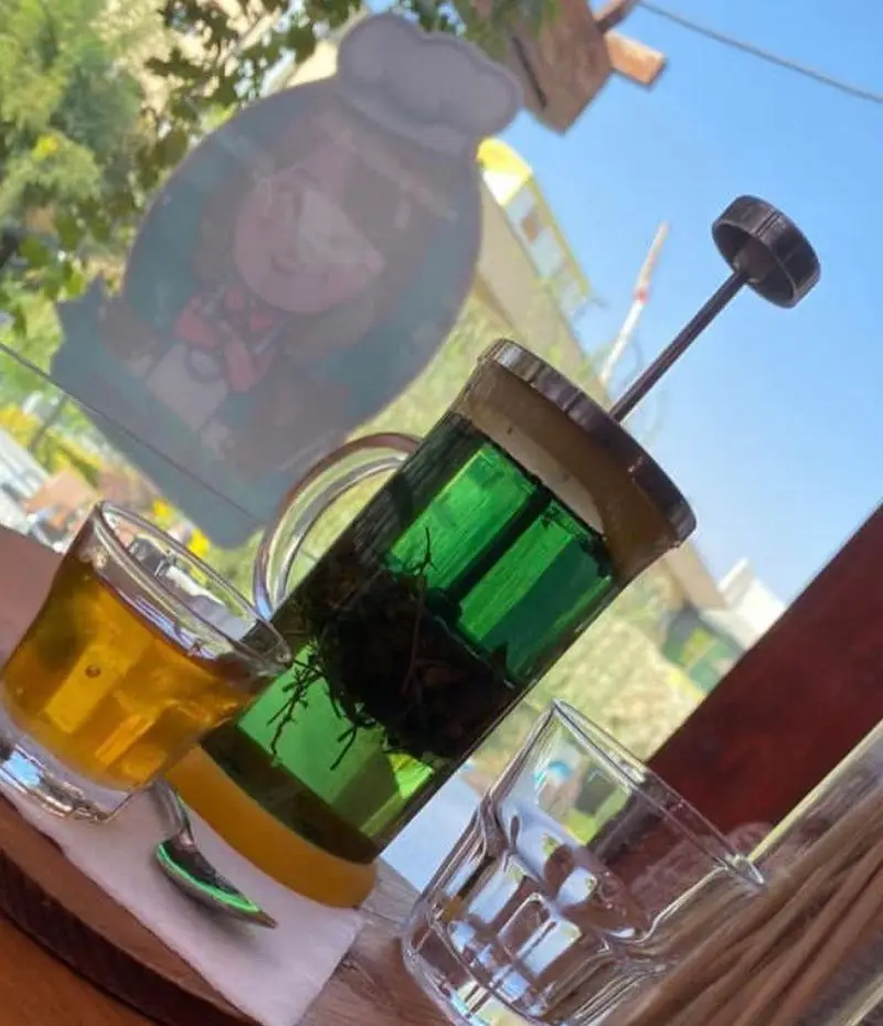 دمنوش گیاهی تازه در فرنچ پرس، لیوان عسل یا چای و لیوان خالی برای سرو در محیط آرام و دلنشین کافه مونو. لحظاتی لذت بخش در کافه.