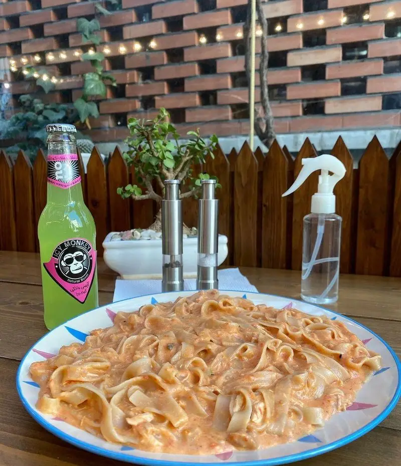 پاستا خوشمزه با سس کرمی در کافه مونو، همراه با نوشیدنی خنک آیس مانکی در فضای دلنشین و باز رستوران.