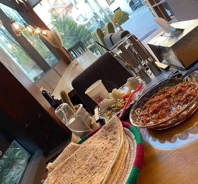 تجربه یک وعده غذایی لذیذ در کافه مونو: میز پر از نان تازه، خوراک سنتی ایرانی، مخلفات خوش‌رنگ و نوشیدنی در فضایی آرام و دلنشین.