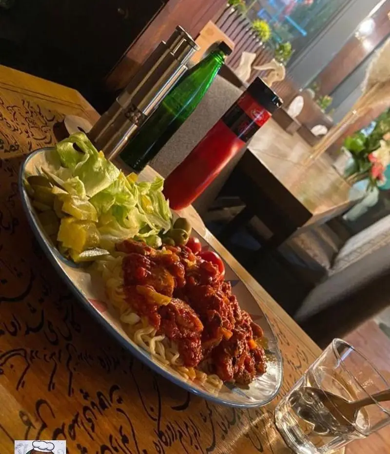 یک بشقاب پاستای لذیذ با سس غنی، سالاد تازه، ترشی و زیتون در محیط گرم و هنری کافه مونو. غذای باکیفیت در کافه رستوران مونو.