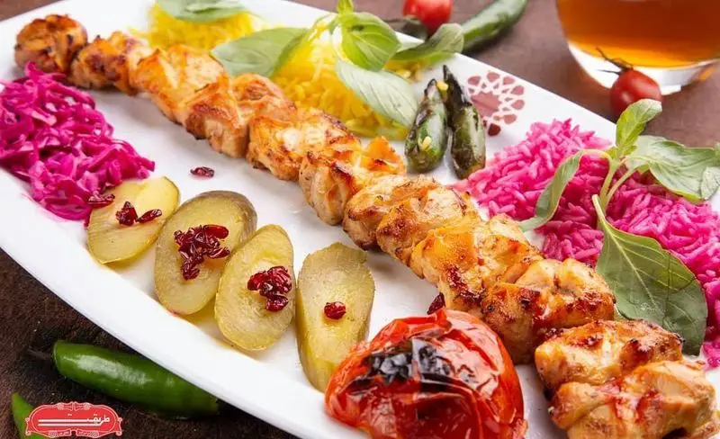 غذای دلپذیر رستوران طریقت شعبه غرب شامل جوجه کباب، برنج زعفرانی و صورتی، خیارشور، سالاد کلم و گوجه کبابی. تجربه‌ای لذیذ از غذای ایرانی.