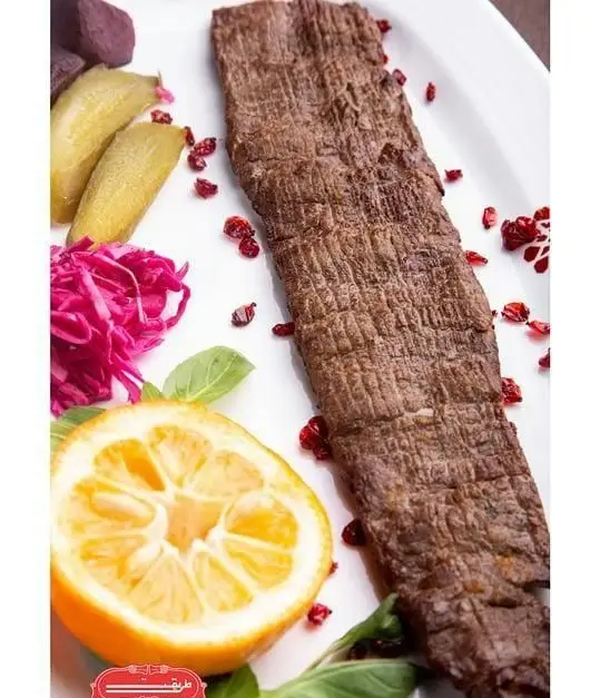 کباب برگ لذیذ رستوران طریقت (شعبه غرب) به همراه زرشک، برش لیمو، خیارشور و کلم قرمز ترشی؛ یک غذای ایرانی خوشمزه.