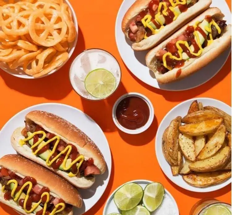 هات داگ‌های خوشمزه نویدا با سس، سیب‌زمینی وجز، چیپس چرخ‌فلکی و نوشیدنی لیمویی. تجربه فست فود عالی در رستوران نویدا.