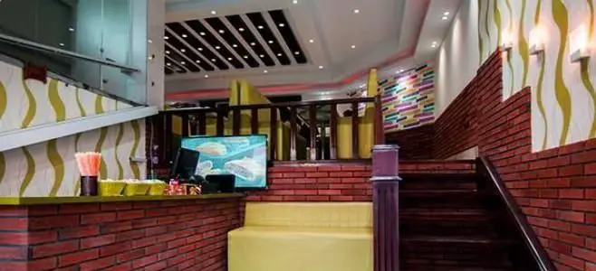 دکوراسیون داخلی شیک و مدرن فست فود پانچیک با میز سفارش، نشیمن های زرد، پله های آجری و نورپردازی دلنشین و طراحی منحصر به فرد.