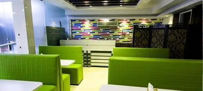 فضای داخلی شیک و مدرن فست فود پانچیک با مبلمان راحتی سبز روشن، میزهای سفید و دکوراسیون جذاب برای تجربه غذایی لذت‌بخش.