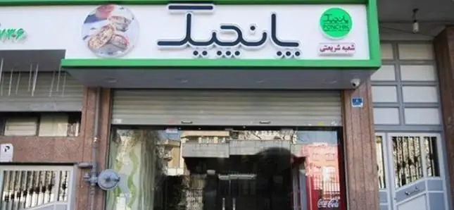 عکس نمای روبروی فروشگاه و تابلوی بزرگ فست فود پانچیک، شعبه شریعتی، با طراحی سبز و سفید و دسر پنکیک.