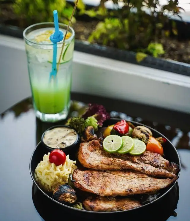 غذای اصلی لذیذ رستوران رزاموند: فیله مرغ گریل شده با پوره سیب زمینی، سبزیجات تازه، سس قارچ و نوشیدنی خنک در محیط دلنشین.